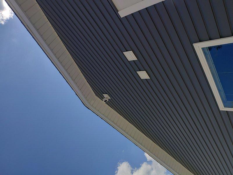 Installed four hardwired Ring security cameras on residential property with no existing fixtures or electrical boxes. Ran new wiring through attic space, sourcing power from garage door opener circuit. Mounted two floodlight cameras on siding blocks at rear and right-side roof peaks, installed standard camera on left roof peak with siding block, and mounted fourth standard camera in old work box on patio soffit above sliding glass door. All cameras hardwired and operational upon completion.