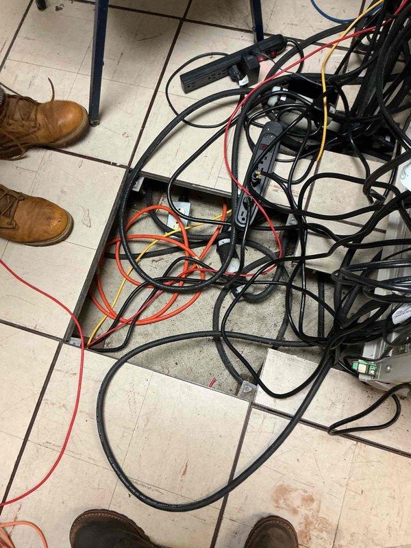 Conducted electrical estimate for generator installation serving a portion of the building. Assessed existing site conditions including weathered exterior infrastructure with rusted metal conduit, concrete foundation areas showing environmental wear, and gravel pathways with vegetation growth. Evaluated interior electrical distribution system with extensive bundled cable routing across tiled work area. Documented existing conditions through photographic survey to support generator sizing, load calculations, and electrical connection requirements for estimate development.