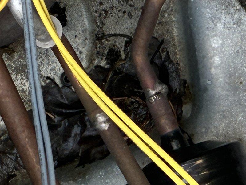 Completed preventive maintenance service on residential air conditioning system. Inspected mechanical components, refrigerant lines, and utility connections in crawlspace area, noting age-related weathering on copper piping. Examined and documented air filter condition, which showed moderate dust accumulation within diamond-mesh filtration media.