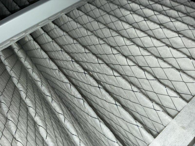 Completed preventive maintenance service on residential air conditioning system. Inspected mechanical components, refrigerant lines, and utility connections in crawlspace area, noting age-related weathering on copper piping. Examined and documented air filter condition, which showed moderate dust accumulation within diamond-mesh filtration media.