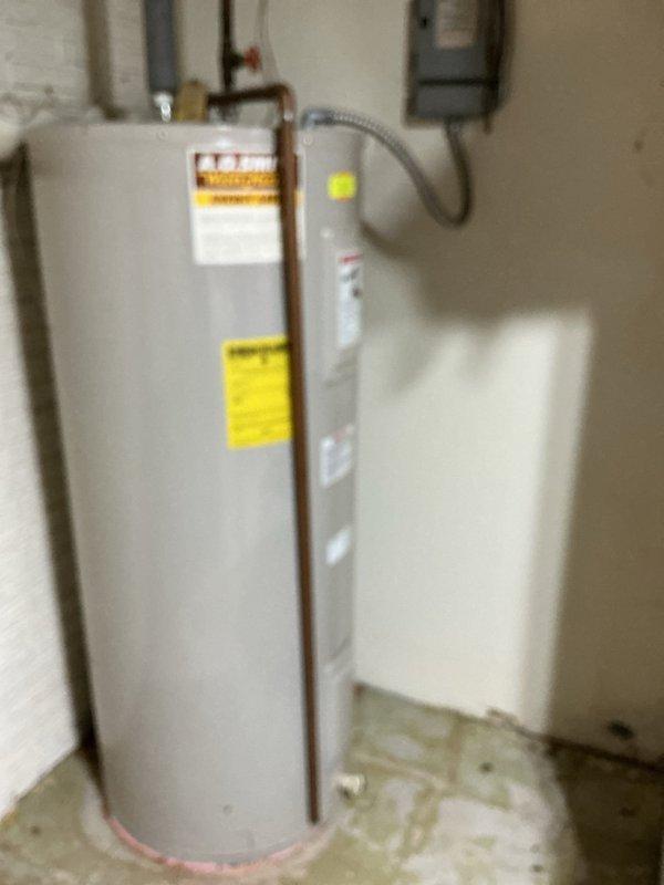 Completed diagnostic evaluation of residential tanked water heater system. Inspected water heater unit and surrounding plumbing infrastructure, noting moisture staining on concrete floor at base of tank and evidence of historical water damage on adjacent wall surfaces near valve assembly. Assessed expansion tank condition and plumbing connections at top of unit, including copper supply lines and flexible connectors. Evaluated red-handled valve assembly and associated PVC piping showing age-related wear and discoloration. Examined shower fixture for reported leak condition. Documented all findings with photos for customer review. Provided quote for expansion tank replacement as requested. System evaluation complete with recommendations for necessary repairs to address moisture issues and prevent further water damage.