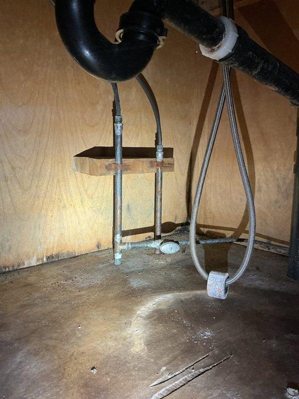 Completed comprehensive whole home plumbing inspection for recently purchased residence, including evaluation of hot water tank of unknown age. Documented existing plumbing infrastructure including under-sink drain trap with visible mineral buildup at connections, rigid metal supply lines, and flexible braided supply hose. Assessed basement utility area plumbing systems including PEX water lines, PVC drainage piping, and metallic piping with evidence of corrosion staining at ceiling penetrations. All accessible plumbing components photographed and evaluated for condition and compliance.