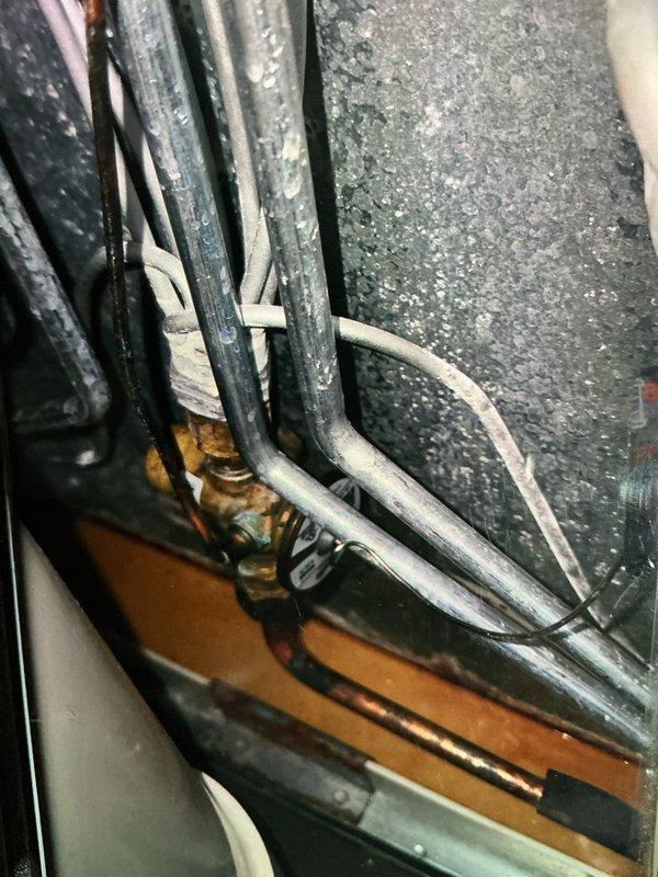 Completed routine maintenance visit on a 3-year-old air conditioning system under MVP recurring service agreement. Upon inspection, discovered heavy frost and ice buildup on the evaporator coil, indicating restricted airflow or possible refrigerant issue. Documented refrigerant line set condition in mechanical space, noting proper insulation and secure bundling of copper tubing with appropriate fasteners against concrete block wall.