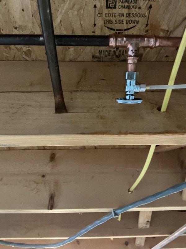Responded to low water pressure complaint at refrigerator water line. Upon inspection, located copper supply line with corroded fitting and undersized blue PEX connection in ceiling joist area above kitchen. Customer had recently installed new water softener and water heater, which likely exposed existing restriction in refrigerator supply line. Assessed piping configuration and identified fitting as primary cause of reduced flow to appliance. Documented existing copper-to-PEX transition point showing oxidation and potential flow restriction requiring correction to restore adequate water pressure to refrigerator ice maker and dispenser.