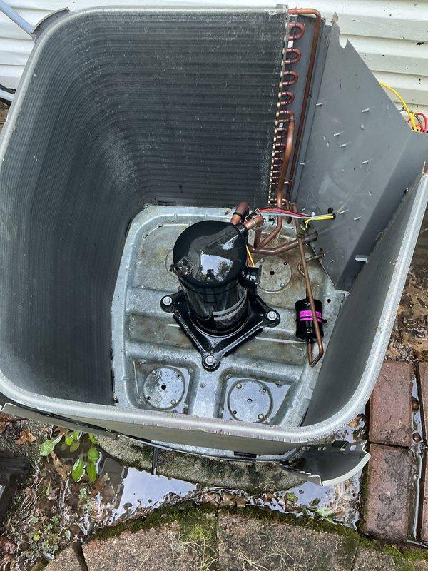 Performed comprehensive preventive maintenance on a 6-year-old residential air conditioning system located on ground-level concrete pad. Removed top panel and inspected all internal components including compressor, condenser coil, refrigerant lines, and electrical connections. Noted moderate dust and dirt accumulation on condenser coil fins requiring cleaning. Verified compressor mounting and isolation grommets were secure and properly positioned. Inspected copper refrigerant lines and connections for signs of wear or leakage. Checked electrical conduit routing and cable connections along exterior wall. Cleared debris, fallen leaves, and organic material from around unit base and concrete pad to ensure proper airflow and drainage. System operational and functioning within normal parameters upon completion of maintenance service.