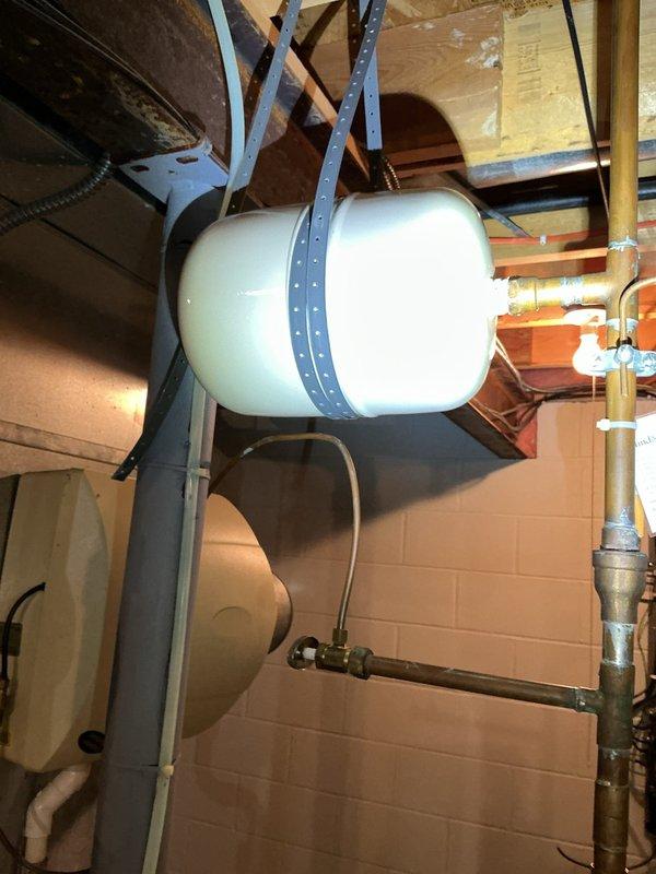 Responded to callback for expansion tank leak on recently installed water heater system. Upon inspection, confirmed thermal expansion tank was actively leaking and required replacement. Removed failed expansion tank that was properly suspended from ceiling joists with metal strapping. Installed new thermal expansion tank, secured with appropriate mounting hardware to structural members, and reconnected to domestic water supply system. Verified all connections were properly sealed, tested system for leaks, and confirmed proper operation of pressure relief components.