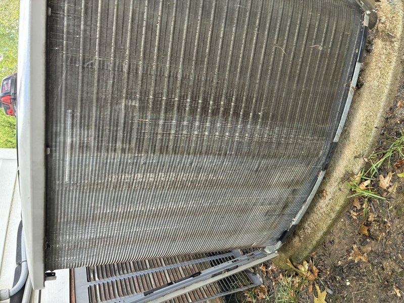 Completed BS-MVP recurring cooling maintenance visit on outdoor condensing unit. Upon arrival, found condenser coil fins heavily soiled with substantial accumulation of dirt, leaves, pine needles, and organic debris significantly restricting airflow. Performed thorough coil cleaning to remove all contamination and restore proper airflow through the unit. Inspected condenser fan motor, refrigerant lines, and cabinet assembly - all components found in operational condition. Unit tested and operating within normal parameters following service. Documentation photos captured showing before and after conditions of coil cleaning work performed.