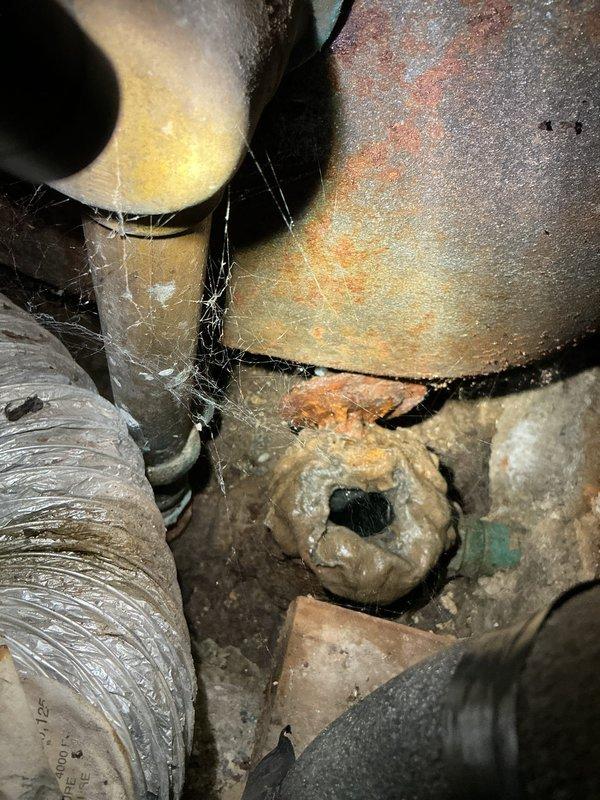 Responded to plumbing service call for toilet leak at base and drainage issues in bathroom fixtures. Upon inspection, identified deteriorated wax ring seal causing water seepage around toilet base. Removed and reset toilet with new wax ring and closet bolts to eliminate leak. Assessed tub and sink drainage problems, finding partial blockages in drain lines. Performed mechanical augering of bathroom drain system to clear obstructions and restore proper flow. Inspected accessible plumbing connections in crawlspace beneath bathroom, noting significant corrosion on metal fittings and aging pipe insulation. Tested all fixtures after repairs to verify proper drainage and confirmed no active leaks at toilet base. Recommended monitoring corroded piping components for potential future service needs.
