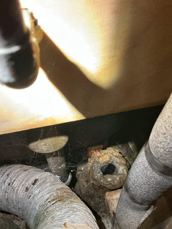 Responded to plumbing service call for toilet leak at base and drainage issues in bathroom fixtures. Upon inspection, identified deteriorated wax ring seal causing water seepage around toilet base. Removed and reset toilet with new wax ring and closet bolts to eliminate leak. Assessed tub and sink drainage problems, finding partial blockages in drain lines. Performed mechanical augering of bathroom drain system to clear obstructions and restore proper flow. Inspected accessible plumbing connections in crawlspace beneath bathroom, noting significant corrosion on metal fittings and aging pipe insulation. Tested all fixtures after repairs to verify proper drainage and confirmed no active leaks at toilet base. Recommended monitoring corroded piping components for potential future service needs.