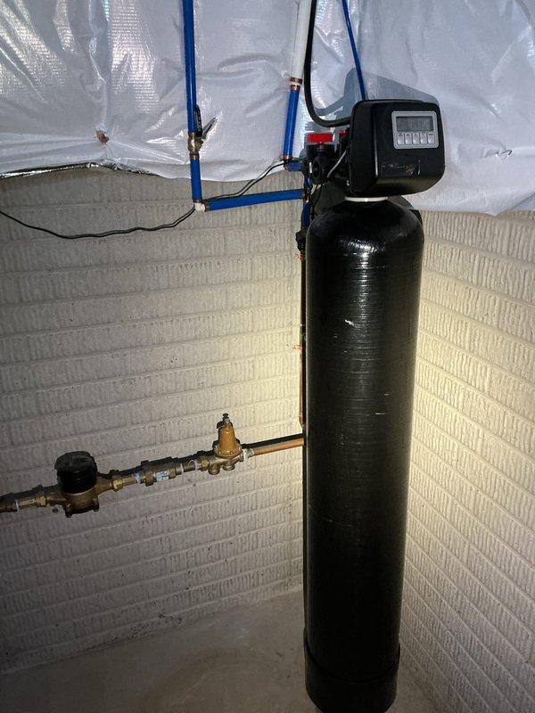 Responded to service call for water softener continuously draining water at residential property. Upon arrival, confirmed bypass valve had been closed by homeowner to prevent ongoing water discharge. Performed diagnostic inspection of water softener system including control head, valve assembly, and drain line connections. Examined digital control head display for error codes and cycle status. Inspected copper piping, brass fittings, and PEX connections for proper operation and potential leaks. Evaluated pressure regulator and valve components mounted to main water line. Assessed overall system installation including tank condition, plumbing configuration, and control settings. Documented equipment condition with photographs showing control head unit with barcode BNDO4442801, complete piping assembly, and installation setup in basement utility area. Identified malfunction causing continuous drain cycle and performed necessary repairs to restore normal water softener operation. Tested s