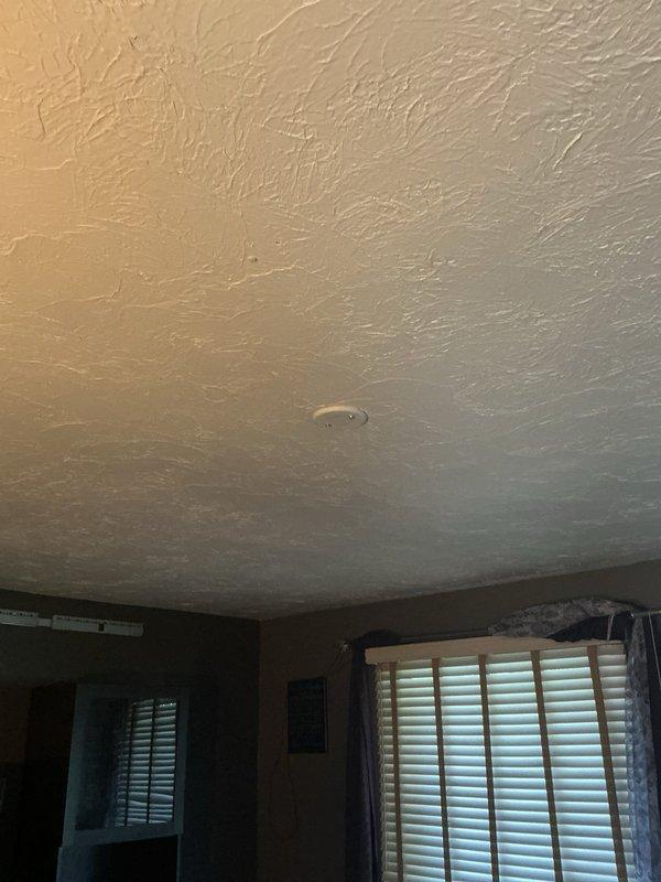 Installed electrical infrastructure for ceiling fan in residential room by tapping power from existing kitchen counter outlet on opposite side of wall. Ran switch leg from single gang box to attic, installed fan-rated junction box at ceiling location, and temporarily covered with blank plate pending homeowner's installation of fan fixture.