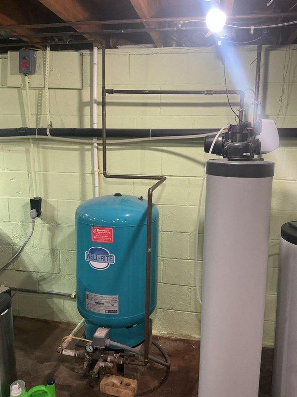 Responded to service call for ongoing water odor issue affecting entire household with 70-year-old home. Inspected tanked water heater system and associated plumbing components in basement utility area. Upon arrival, observed water heater installation alongside pressure tank and water treatment equipment. Conducted thorough diagnostic assessment of water heater unit, checking anode rod condition, sediment accumulation, and temperature settings as potential sources of sulfur or bacterial odor. Examined copper supply lines, inlet/outlet connections, and pressure relief valve for any signs of contamination or system issues. Evaluated pressure tank and filtration system integration with water heater to determine if odor originated from heating unit or upstream water treatment components. Photographed equipment configuration showing water heater with circulation pump assembly, Fil-Rite pressure tank, and associated piping for warranty documentation purposes. Advised customer on findings and