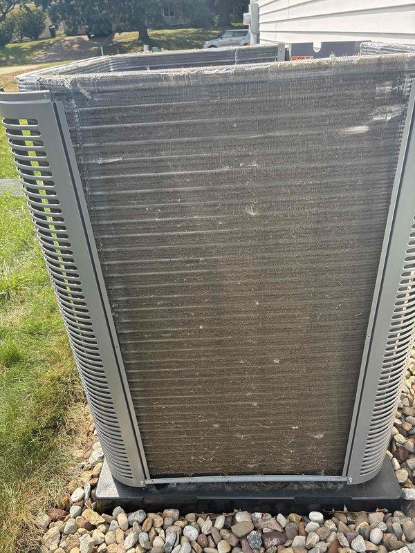 Completed preventive maintenance service on a one-year-old ground-mounted air conditioning condenser unit. Inspected heat exchanger coils and noted significant accumulation of dust, dirt, pollen, and outdoor debris throughout the aluminum fins, with visible discoloration and drainage patterns indicating environmental exposure. Performed thorough cleaning of condenser coils to restore proper airflow and heat transfer efficiency, checked refrigerant lines for proper insulation, verified unit operation, and confirmed system is ready for continued cooling season performance.