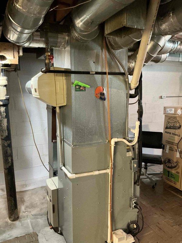 Conducted comprehensive HVAC system evaluation for equipment replacement estimate. Assessed existing gas furnace/air handler unit located in basement utility area, including connected ductwork distribution system, copper refrigerant lines, and electrical connections. Evaluated outdoor condensing unit positioned on concrete pad adjacent to building foundation, inspecting refrigerant line sets, electrical conduit routing, and overall system configuration. Documented current equipment specifications, installation conditions, and provided replacement recommendations based on system age and performance requirements.