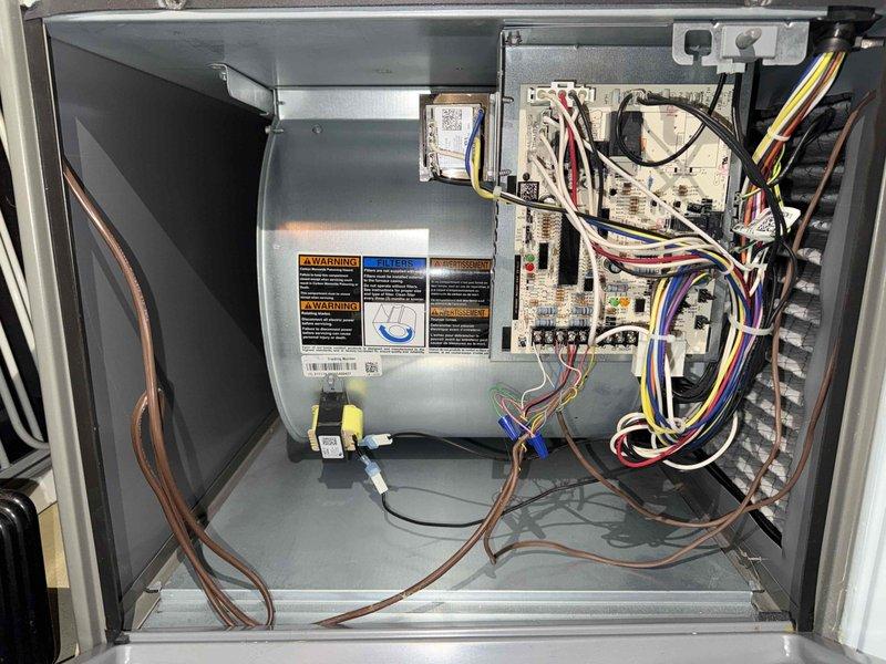 Completed BS-MVP cooling maintenance visit on 4-year-old air conditioning system. Upon inspection, discovered significant frost buildup on evaporator coil fins, indicating restricted airflow or potential low refrigerant charge. Opened unit cabinet and documented internal components including blower assembly, control board, wiring harnesses, and refrigerant line connections—all appeared in normal operating condition with proper wire routing and no visible damage. Photographed frosted coil condition and electrical system for service records. The frost accumulation on the heat exchanger requires follow-up to determine root cause, which may include dirty air filter, blocked return air, low refrigerant levels, or malfunctioning blower motor affecting proper air circulation across the coil.