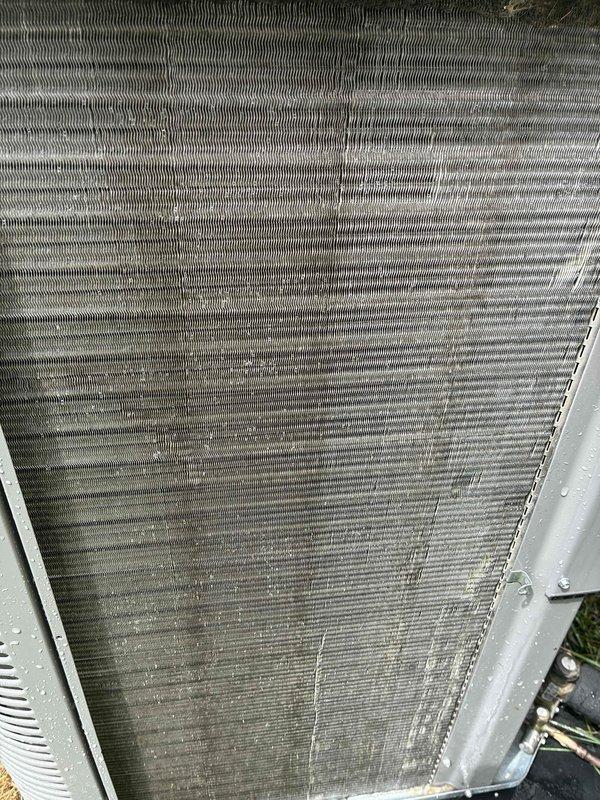 Completed biennial preventive maintenance inspection on residential air conditioning system. Thoroughly cleaned outdoor condenser coil which exhibited moderate to heavy accumulation of dirt, dust, and organic debris throughout the fin surfaces. Inspected indoor evaporator coil assembly in attic installation, noting normal operational condensation and light dust accumulation on serpentine coil pattern. Verified refrigerant line connections, brass fittings, and insulation integrity on both suction and liquid lines. Checked electrical connections and control wiring. System operating within normal parameters following maintenance service.