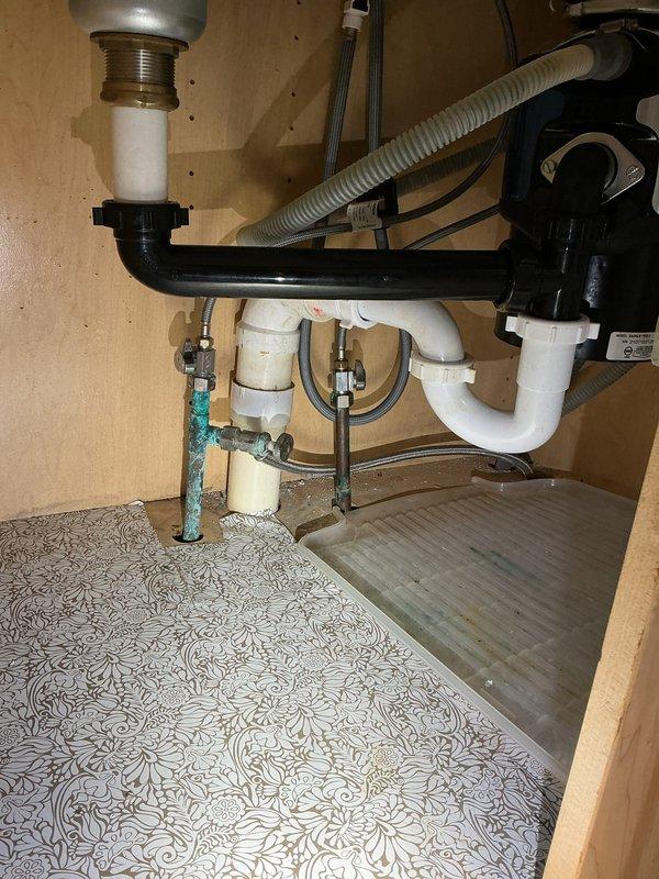 Responded to water leak originating from kitchen sink causing basement flooding. Upon inspection, identified compromised P-trap assembly and deteriorated supply line connections under kitchen sink with visible corrosion on shut-off valve. Documented extensive water damage to basement ceiling and walls, showing prolonged moisture intrusion with significant staining, surface deterioration, and structural compromise to drywall materials. Assessed plumbing configuration including PVC drain assembly, appliance connections, and supply lines to determine leak source and extent of damage requiring remediation.