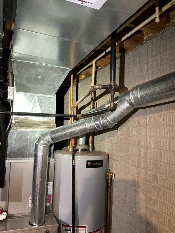 Provided no-cost estimate for replacement of existing 40-gallon natural gas atmospheric vented water heater experiencing active leak at base. Customer requested quote for upgraded 50-gallon capacity unit. Inspected current Lochinvar water heater installation in basement mechanical room, documented existing plumbing connections including copper supply lines with shutoff valves, confirmed natural gas supply line configuration, and assessed venting arrangement with existing galvanized ductwork system. Photographed equipment layout and surrounding HVAC components to ensure proper clearances and code compliance for replacement unit sizing and installation requirements.