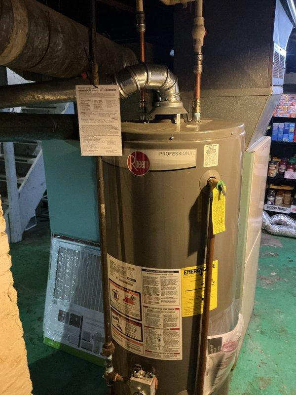 Responded to service call for 40-gallon Rheem Professional gas water heater installed approximately two years ago by company no longer in business. Investigated customer concern regarding gas being trapped in tank due to unit height preventing proper venting. Performed visual inspection of water heater installation, venting configuration, copper supply lines, gas connections, and temperature/pressure relief valve. Documented existing conditions of unit and surrounding mechanical room area. Verified proper clearances and connections at top of unit where copper piping and gas line interface with water heater.