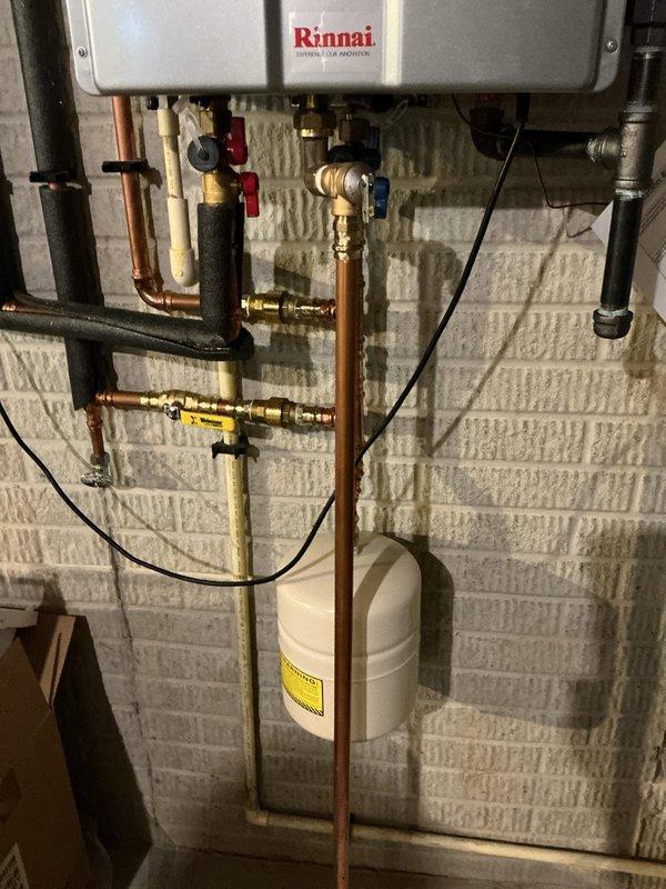 Performed routine preventative maintenance descaling service on Rinnai tankless water heater in 5-year-old residential property. Isolated unit using cold water shut-off valve, connected descaling pump to service valves, and circulated descaling solution through heat exchanger to remove mineral buildup and scale deposits. Flushed system thoroughly with clean water, verified all connections at copper and CPVC piping, checked expansion tank pressure, and confirmed proper operation of all isolation valves including red and blue-handled service valves. Unit restored to normal operation with no reported issues or symptoms prior to service.
