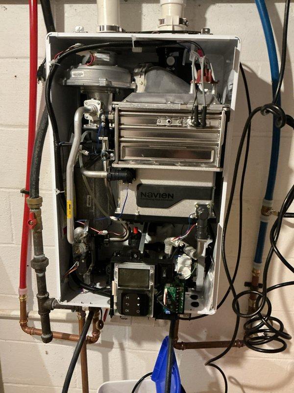 Performed descaling maintenance service on an 11-year-old Navien natural gas tankless water heater. Flushed the unit's heat exchanger to remove mineral buildup, cleaned the inlet filter screen which showed visible sediment accumulation, and verified proper operation of all internal components including the heat exchanger, pump assembly, and control panel.