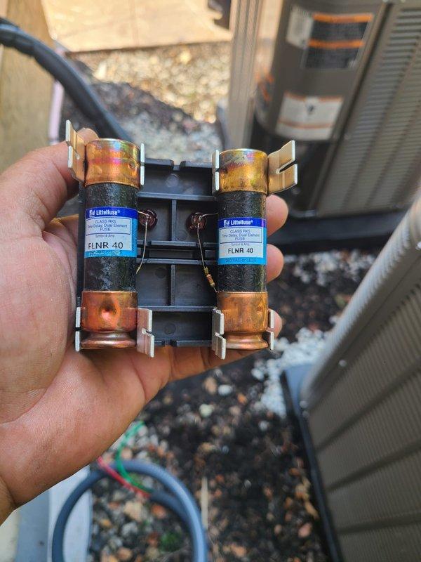 Completed installation of dual Lennox air conditioning condensing units with new coils as first AC system for the property. Replaced failed FLNR 40 amp fuses during installation, mounted both outdoor units on vibration-isolating pads with proper clearances, and connected refrigerant lines and electrical service including conduit runs along exterior wall.