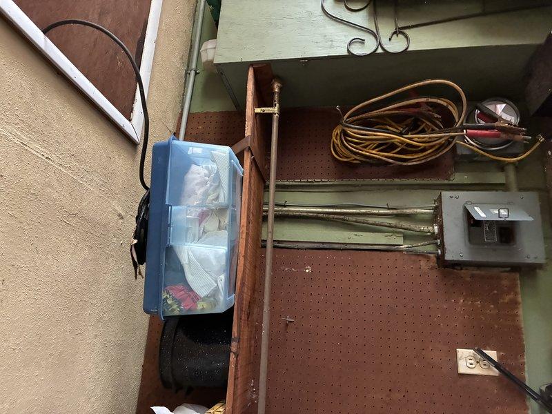 Responded to no power call at residential property. Upon arrival, inspected exterior electrical service entrance and utility connection point on home with light green siding. Verified service drop connection and metering equipment. Proceeded to interior utility/workshop area to assess main electrical panel and distribution system. Inspected main service panel mounted on pegboard wall, checked breaker positions, and verified proper connections. Identified and resolved power issue, restoring electrical service to the residence. System tested and confirmed operational upon completion.