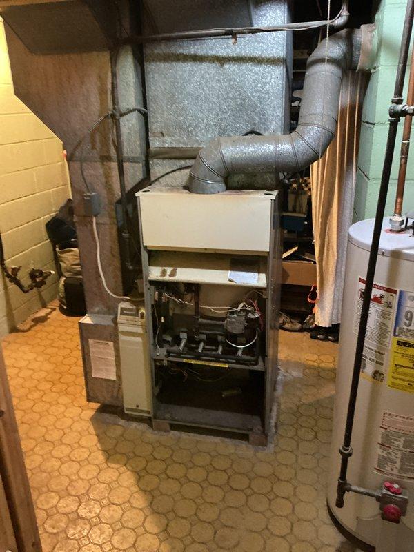 Completed full HVAC system installation including an 80% AFUE gas furnace in the basement mechanical room and matching outdoor air conditioning condenser unit. The furnace was positioned on the existing hexagonal tile floor with proper clearances from the adjacent water heater and utility connections. Installed metallic flexible ductwork connecting the furnace to the existing distribution system, ensuring secure transitions and proper support. The outdoor condenser unit was set on a concrete pad against the building's exterior siding with appropriate clearances from landscaping elements including ornamental shrubs and ground cover. Mounted electrical disconnect box on the building siding with conduit run to the condenser unit per code requirements. Verified all refrigerant line connections, electrical wiring, gas piping, and condensate drainage. System was tested for proper operation, airflow, and temperature differential across both heating and cooling modes.