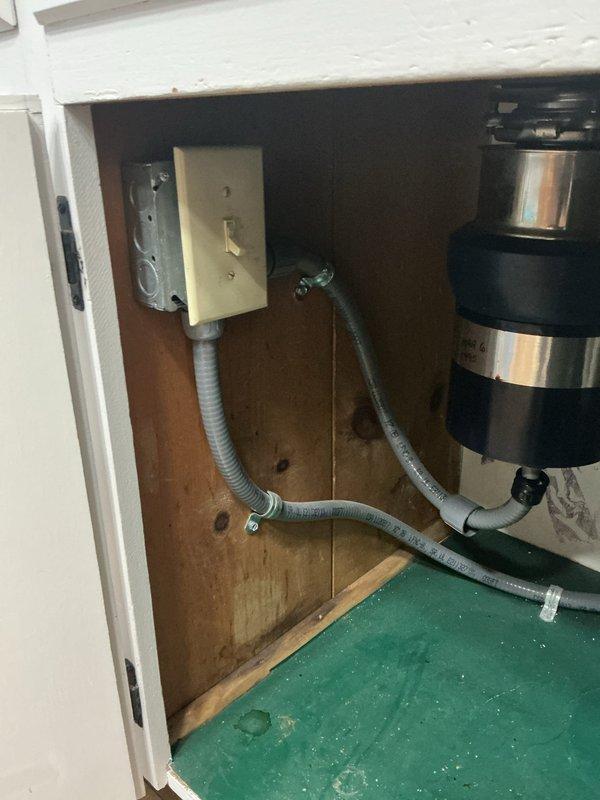 Hardwired garbage disposal unit to existing electrical circuit located beneath kitchen sink. Converted disposal from plug-in outlet connection to permanent electrical connection, utilizing existing wiring infrastructure that was previously installed for under-sink lighting circuit. Completed electrical installation in compliance with code requirements for hardwired appliance connections.