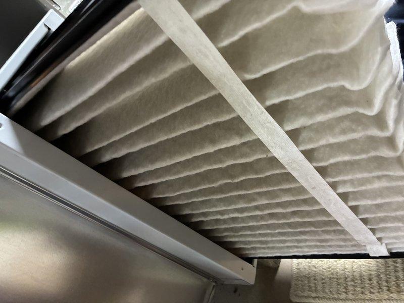 Completed scheduled maintenance visit on a 3-year-old air conditioning system. Inspected and photographed the air filter, which showed clean condition with minimal debris accumulation in the pleated media. Examined the evaporator coil assembly, noting light dust buildup on the vertical fins and cylindrical housing, consistent with normal operation. System operating within normal parameters at time of service.