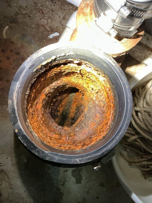 Responded to slow-draining basement floor drain service call. Upon inspection, discovered severely corroded cast iron drain pipe with significant rust buildup and scale accumulation restricting water flow. The deteriorated pipe interior showed extensive oxidation throughout, with compromised structural integrity evident at connection points to PVC drainage system. Documented existing conditions including standing water on basement floor, corroded metal fixtures, and aging plumbing infrastructure requiring attention. Assessed drainage system configuration and identified the corroded pipe section as primary cause of slow drainage issue.