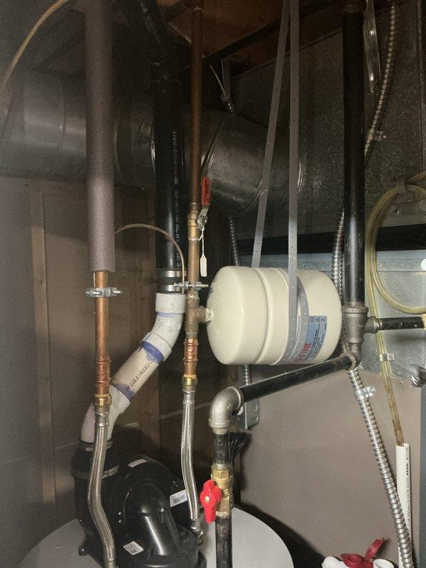 Completed electrical installation warranty inspection following successful approval. Accessed mechanical utility area through floor panel to document required water ground line and bonding connections per inspection requirements. Photographed copper water service piping, grounding electrode conductor connections, and bonding jumpers at water meter location. Documented all bonding connections to metallic water distribution system in accordance with NEC grounding and bonding standards.