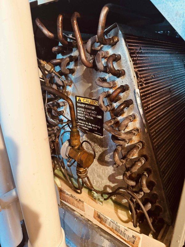Responded to no cooling complaint on 20-year-old air conditioning system. Upon inspection, found heavily oxidized evaporator coil with significant tarnishing on copper tubing and deteriorated heat exchanger assembly. Evaluated control board and electrical components within air handler, noting existing wiring configuration and relay assembly. Documented current system condition with photographic evidence showing advanced age-related degradation of refrigerant coil and control system components for customer review and future service planning.