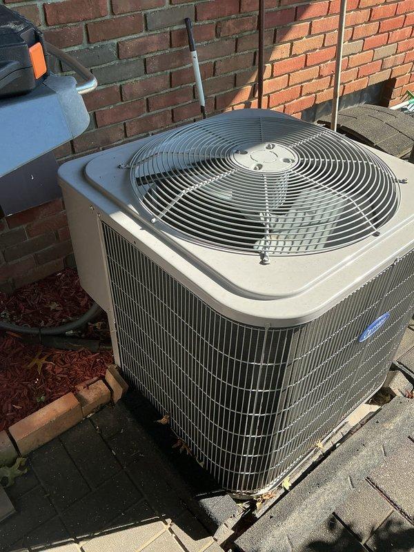 Completed routine maintenance visit on a 10-year-old residential air conditioning system. Performed standard cooling season inspection of outdoor condenser unit, verified proper operation of all components, and documented equipment condition through site photography. Unit found in serviceable condition with electrical disconnect box and refrigerant lines properly secured to exterior brick wall mounting location.