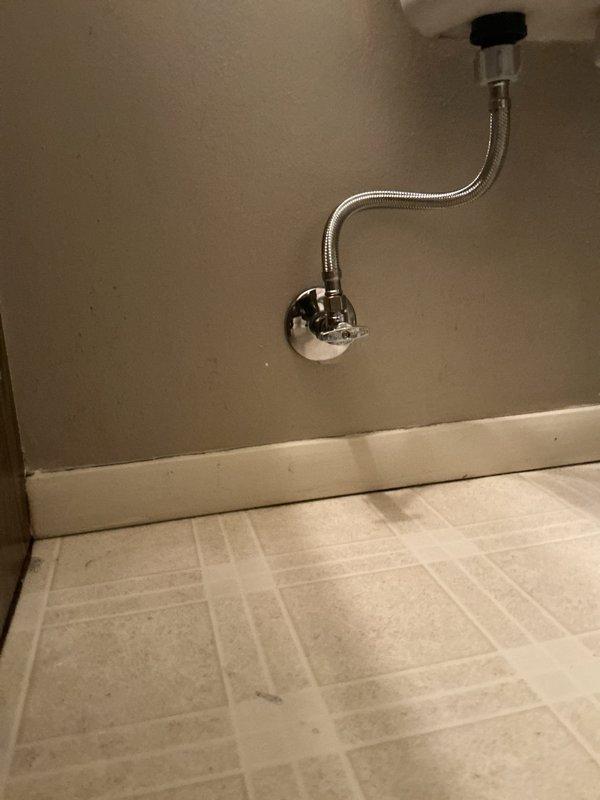 Responded to emergency call for active water leak at toilet supply line in bathroom. Upon arrival, found main water supply had been shut off by homeowner to stop continuous spray from failed shutoff valve connection. Inspected the toilet water supply system and identified compromised angle stop valve and deteriorated braided stainless steel supply line requiring immediate replacement. Removed old valve and supply line, installed new chrome-finished angle stop valve with proper wall escutcheon, and connected new flexible braided stainless steel supply line from wall valve to toilet tank inlet. Restored main water supply, pressurized system, and conducted thorough leak check at all connection points including wall valve, supply line couplings, and tank inlet. Verified proper water flow and shutoff valve operation. Cleaned work area and removed all debris. System tested and confirmed fully operational with no leaks detected.