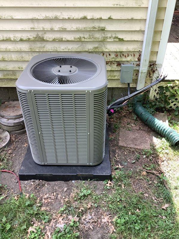 # HVAC Complete System Installation

Completed full HVAC system installation including 90% efficiency furnace, air conditioning condensing unit, and complete ductwork replacement over a two-day period. Installed new gray condensing unit on concrete pad against exterior wall with proper clearances, mounted electrical disconnect box on siding, and ran electrical conduit to unit. Routed refrigerant lines through brick wall using proper penetration techniques with copper lineset running along exterior to connect outdoor condensing unit to indoor air handler. Fabricated and installed complete duct system throughout structure to ensure proper airflow distribution and system efficiency. Tested all electrical connections, verified refrigerant charge, and confirmed system operation within manufacturer specifications.