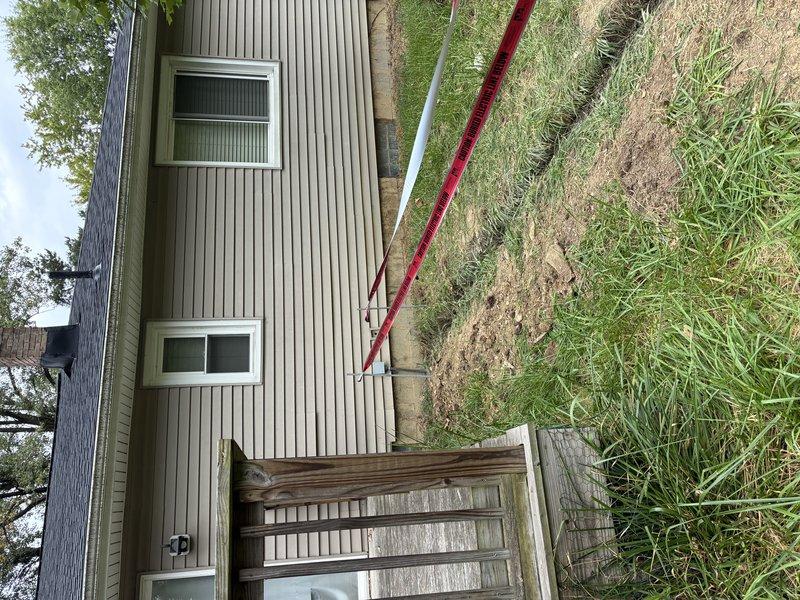 Uncovered electrical trench for required inspection after initial failed inspection. Exposed underground conduit and connections for inspector verification, with electrical panel and outdoor installation prepared for regulatory compliance review.