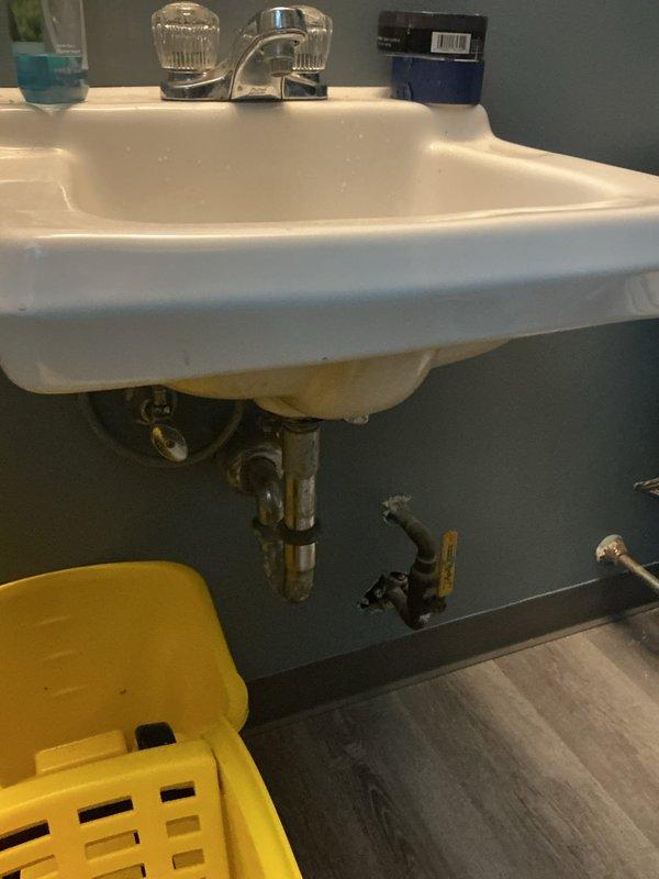 Completed plumbing installation work at commercial restroom facility involving multiple fixture hookups. Successfully installed and connected three-compartment sink system with proper drainage and water supply lines. Installed utility sink with chrome P-trap assembly and shut-off valves mounted to wall. Connected hand sink with chrome faucet featuring acrylic handles, ensuring proper hot and cold water supply connections. Capped one toilet to remove it from service while maintaining water supply integrity to remaining fixtures. All installations tested for leaks and proper drainage. Plumbing work completed to code with exposed chrome piping and shut-off valves accessible for future maintenance.
