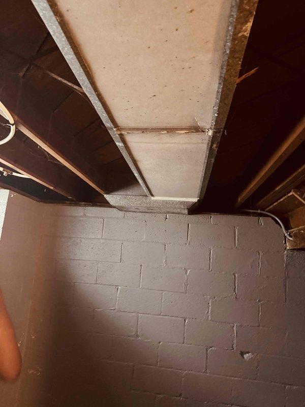 Conducted site assessment for HVAC vent relocation in basement utility area. Documented existing vent location near exposed ceiling joists, copper piping, and concrete block wall construction. Photographed current installation and surrounding conditions including bathroom area with tiled walls to provide detailed information for estimate preparation and approval of proposed relocation work.
