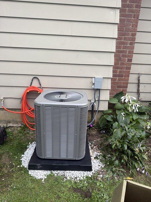 Completed installation of outdoor air conditioning condenser unit with new coil system. Unit was properly mounted on equipment pad with decorative stone base, all refrigerant lines insulated and secured, electrical disconnect installed with 20-amp FLNR fuses, and conduit properly routed along exterior wall. System tested and operational.