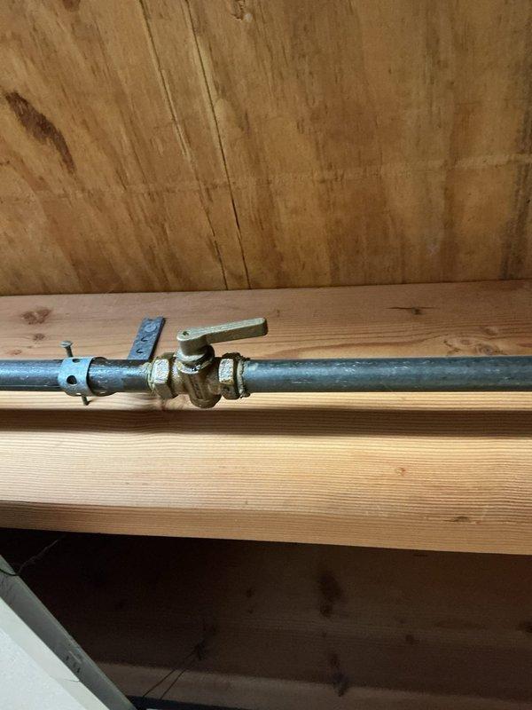 Responded to service call for gas line disconnection in basement. Located and isolated the gas supply line that previously fed a built-in grill. Installed brass ball valve with shutoff capability on the existing galvanized gas pipe run between floor joists. Properly capped the line downstream of the shutoff valve to permanently seal the gas supply, ensuring no gas flow to the disconnected grill appliance. Verified secure mounting of all components to structural framing and confirmed proper installation per gas code requirements.