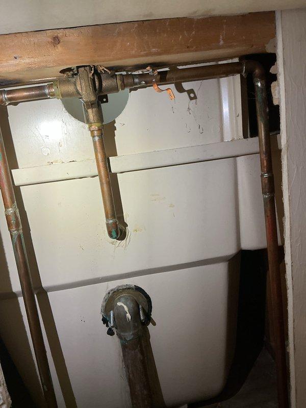 Responded to service call for stuck shower valve affecting two showers on the same water line. Accessed plumbing system through wall opening to inspect brass valve assembly and copper piping connections. Freed the seized valve mechanism, restored water flow to both shower fixtures, and verified proper operation of the system.