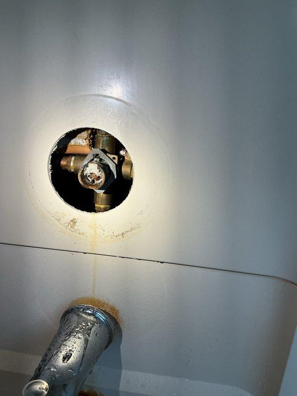 Responded to service call for stuck shower valve affecting two showers on the same water line. Accessed plumbing system through wall opening to inspect brass valve assembly and copper piping connections. Freed the seized valve mechanism, restored water flow to both shower fixtures, and verified proper operation of the system.