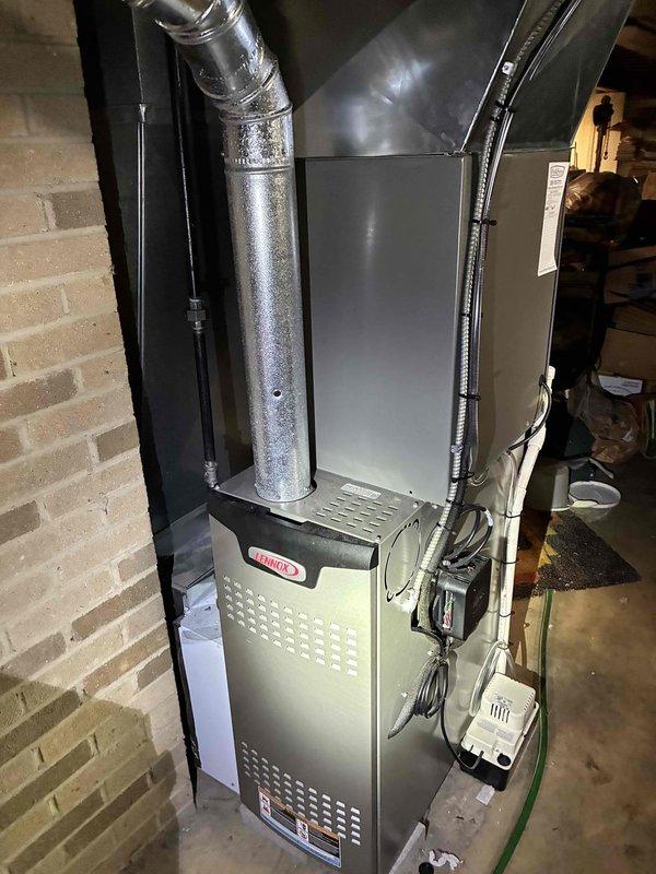 Completed comprehensive MVP air conditioning maintenance service on residential Lennox cooling system and furnace. Performed thorough inspection of outdoor condensing unit, which showed significant weathering and debris accumulation on exterior surfaces and coil fins. Cleaned condenser coils, removed leaves and organic debris from unit base, and verified proper airflow through louvered panels. Inspected indoor furnace system in basement, checked electrical connections and control components, and verified proper operation of blower assembly. Documented equipment condition with photos showing both outdoor AC unit on concrete pad and indoor furnace installation with ductwork connections. All system components tested and confirmed operational for continued cooling season performance.