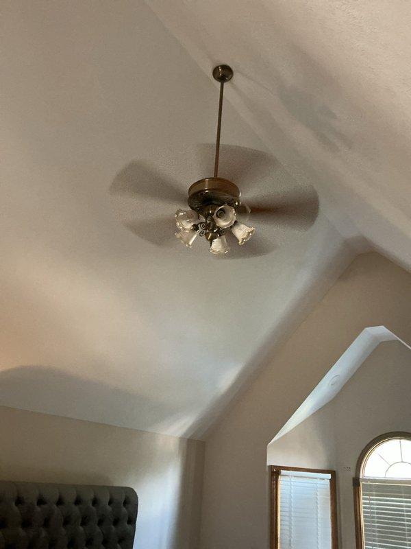 Installed decorative ceiling-mounted light fixture with brass finish and multiple glass globe shades in bedroom with vaulted ceiling. Accessed attic space through existing opening to run electrical wiring and ensure proper fixture support on angled ceiling structure.