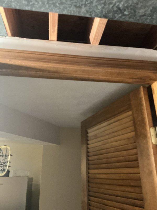 Installed decorative ceiling-mounted light fixture with brass finish and multiple glass globe shades in bedroom with vaulted ceiling. Accessed attic space through existing opening to run electrical wiring and ensure proper fixture support on angled ceiling structure.