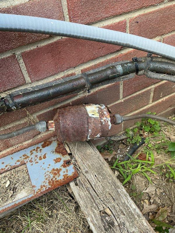 Responded to service call for 20+ year old air conditioning unit producing abnormal operational noises. Upon arrival, performed visual inspection of outdoor condensing unit and associated components. Identified heavily corroded suction line service valve and filter drier assembly showing significant rust deterioration due to prolonged weather exposure. Exterior cabinet panels exhibited surface weathering and minor rust staining consistent with unit age. Conducted operational assessment to identify noise source and verified proper fan motor operation. Documented existing corrosion on refrigerant line components and overall equipment condition through photographic evidence for customer records.