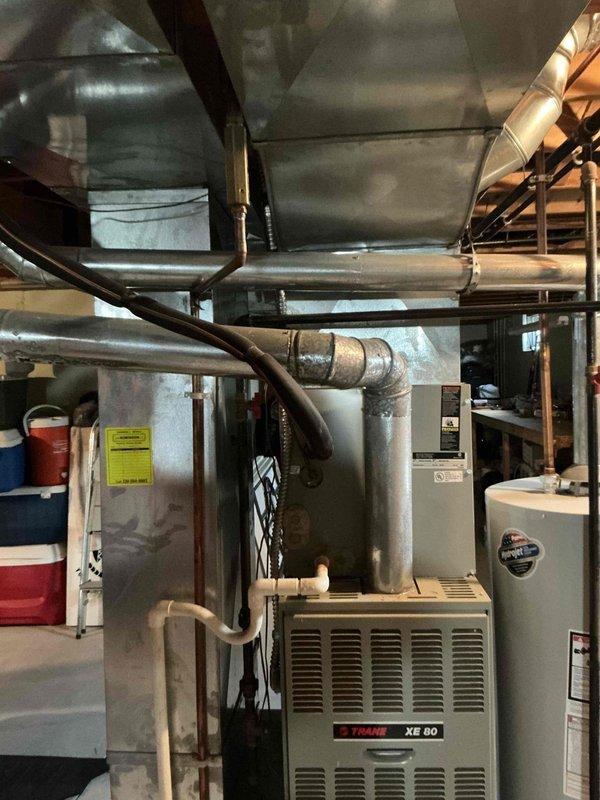 Completed comprehensive estimate for full HVAC system replacement of existing 30-year-old Trane XE 80 furnace and outdoor condensing unit. Assessed basement furnace installation including ductwork configuration and exterior condenser unit positioned on concrete pad, documenting current system condition and equipment specifications for replacement proposal.
