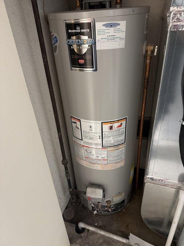 Responded to service call for leaking tanked water heater. Upon inspection, confirmed active leak from Bradford White Defender Safety System water heater tank requiring replacement. Assessed existing installation including copper supply lines, heat trap assembly, shutoff valves, and venting system. Documented unit specifications and current plumbing configuration with photos showing tank condition, valve locations, and connection points. Provided estimate for new tanked water heater replacement unit.