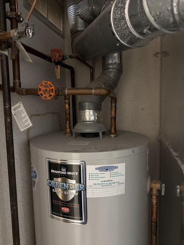 Responded to service call for leaking tanked water heater. Upon inspection, confirmed active leak from Bradford White Defender Safety System water heater tank requiring replacement. Assessed existing installation including copper supply lines, heat trap assembly, shutoff valves, and venting system. Documented unit specifications and current plumbing configuration with photos showing tank condition, valve locations, and connection points. Provided estimate for new tanked water heater replacement unit.